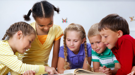 Portrait of pupils looking at page of encyclopaedia at reading lesson