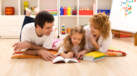 Happy family laying on the floor reading in the kids room
